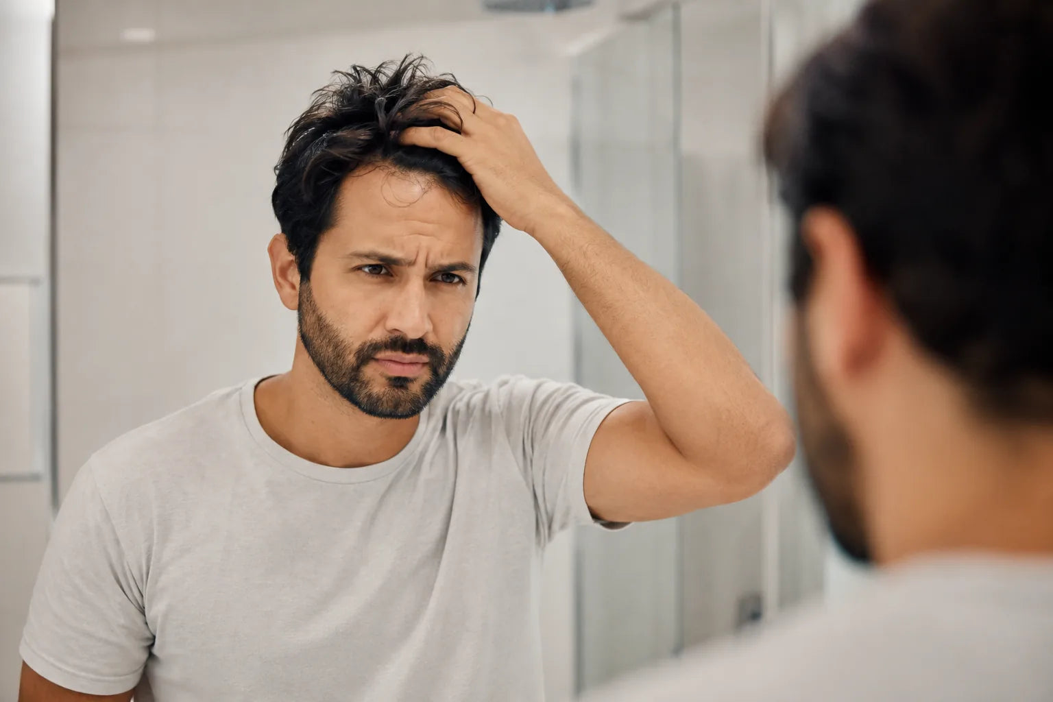 Homem frustrado olhando no espelho com cabelo bagunçado
